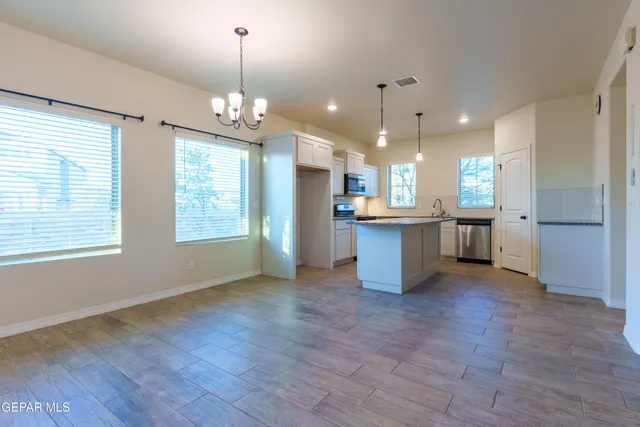 a view of a kitchen with kitchen island a sink wooden floor and living room view