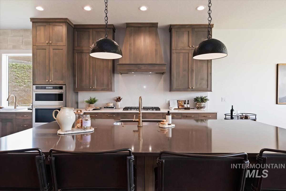 7615 Brown Way Eagle, ID 83714 - Photo 16 of 43 Spacious kitchen featuring a large central island with seating, dark wood-finish cabinetry, stainless steel built-in appliances, and recessed lighting