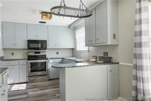a kitchen with stainless steel appliances granite countertop a sink a stove a microwave and cabinets