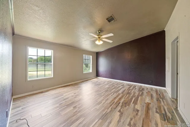 a view of an empty room with window and wooden floor