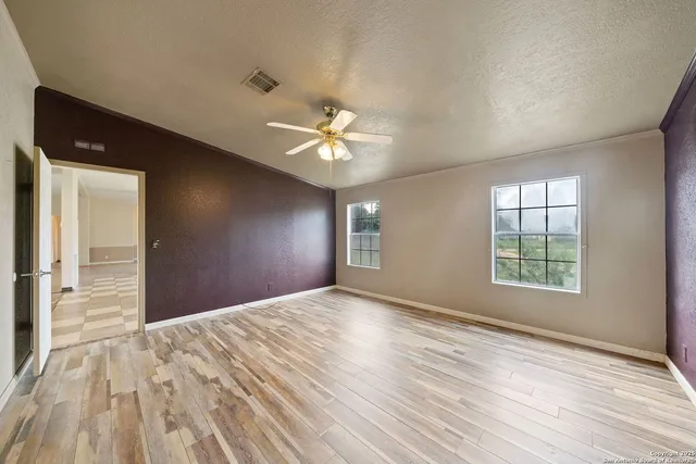a view of a big room with windows and chandelier fan