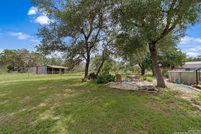 a view of a backyard with table and chairs and a tree