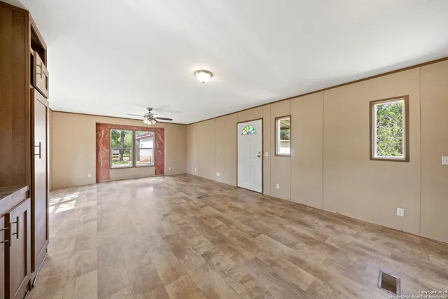 a view of an empty room with window and wooden floor