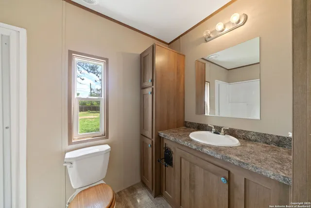 a bathroom with a granite countertop sink toilet and mirror