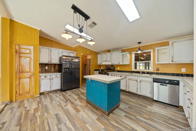 a kitchen with stainless steel appliances a stove top oven a refrigerator cabinets and living room view