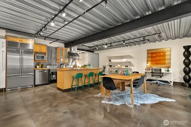 a kitchen with stainless steel appliances kitchen island granite countertop a table chairs and a refrigerator