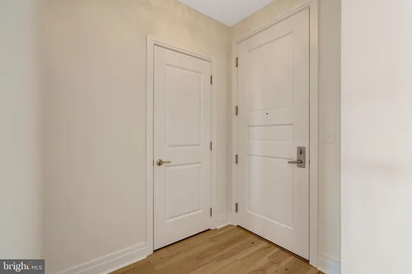 a view of a hallway with wooden floor and a bathroom