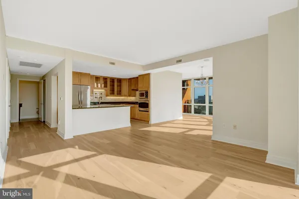 a large kitchen with stainless steel appliances kitchen island granite countertop a refrigerator a stove and a sink with wooden floor