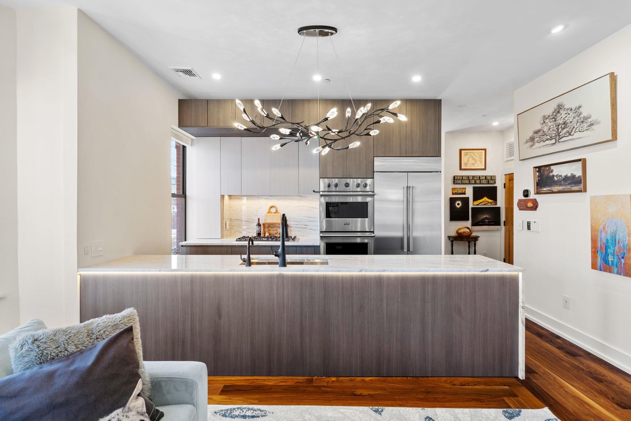 277 York Street, Unit 501 Jersey City, NJ 07302 - Photo 5 of 18 a room with stainless steel appliances kitchen island granite countertop a refrigerator a sink dishwasher a dining table and chairs with wooden floor