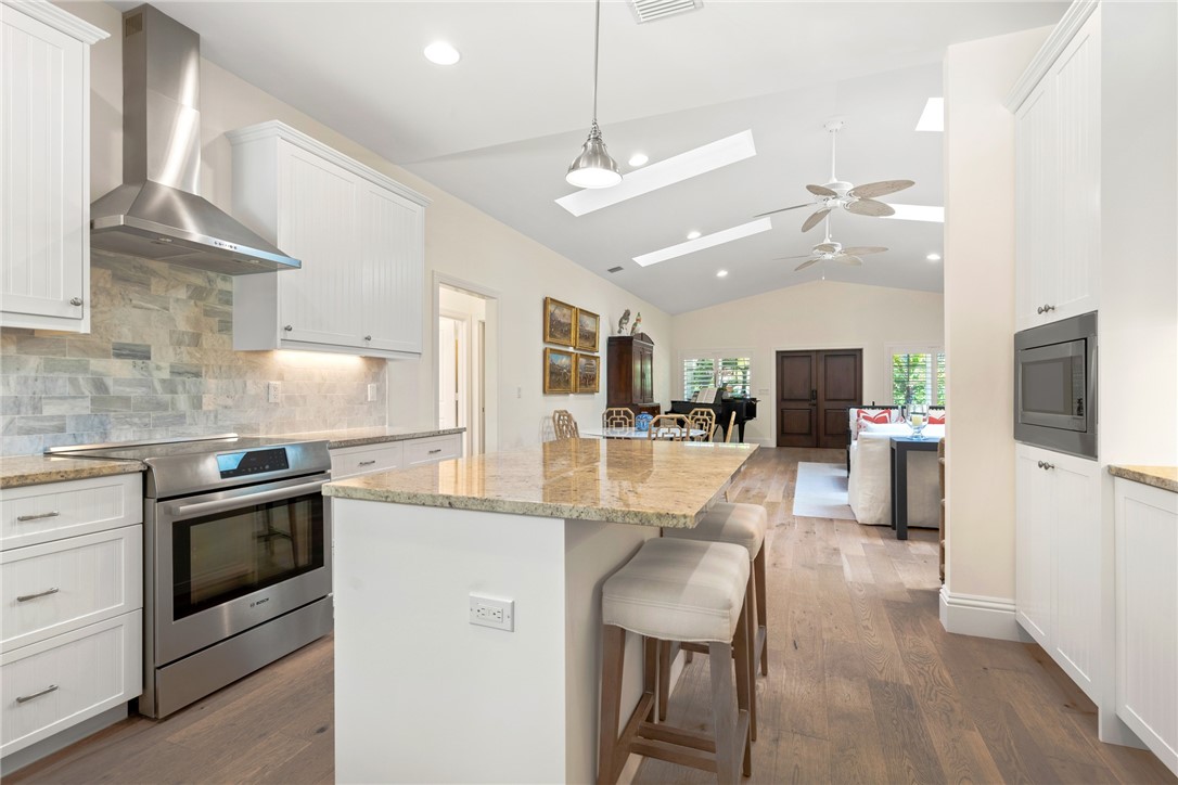 548 Conn Way Vero Beach, FL 32963 - Photo 21 of 34 a kitchen with stainless steel appliances kitchen island granite countertop a stove top oven a sink a dining table and chairs with wooden floor