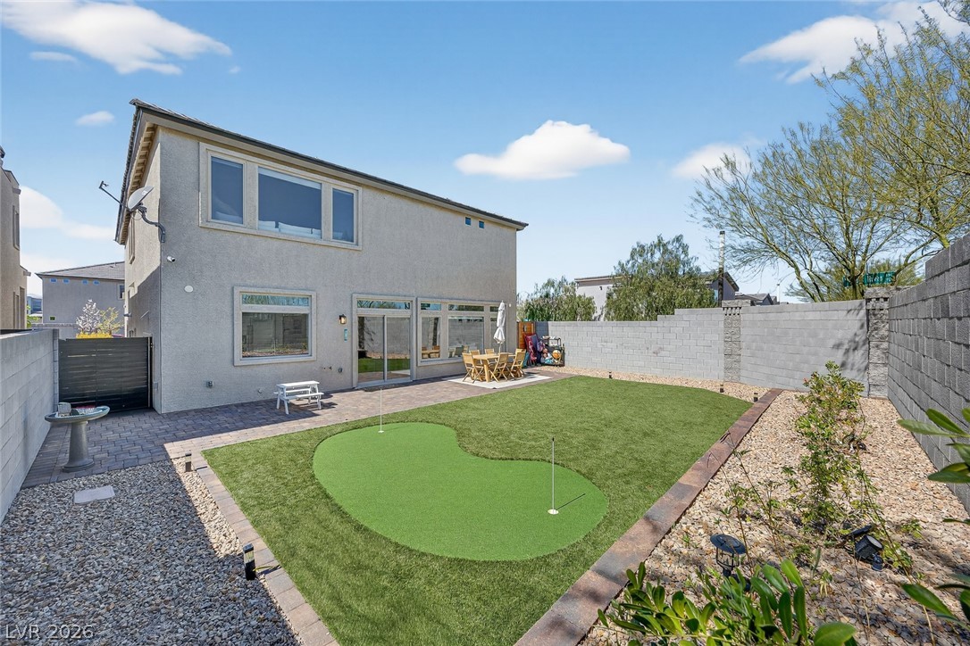 10446 Emerald Rye Street Las Vegas, NV 89183 - Photo 29 of 37 A private backyard oasis features a putting green and a paved patio area.