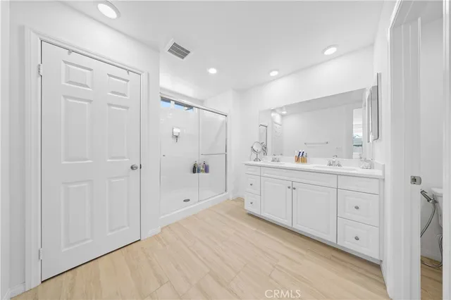 a spacious bathroom with a shower a sink and a mirror