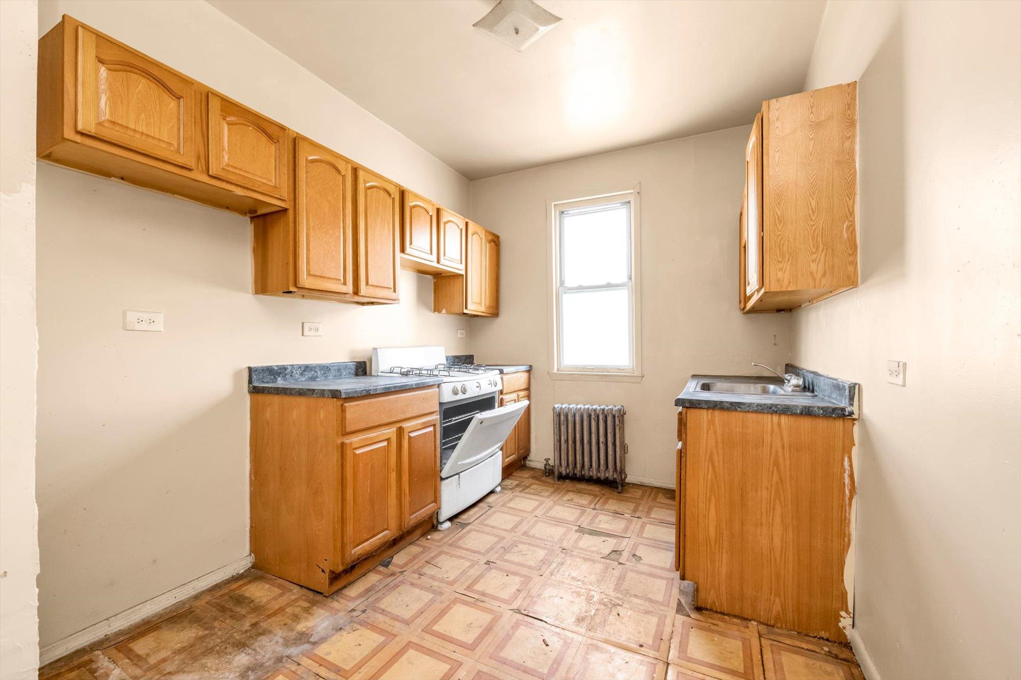1129 East Tremont Avenue Bronx, NY 10460 - Photo 6 of 14 a kitchen with stainless steel appliances granite countertop a sink stove and refrigerator