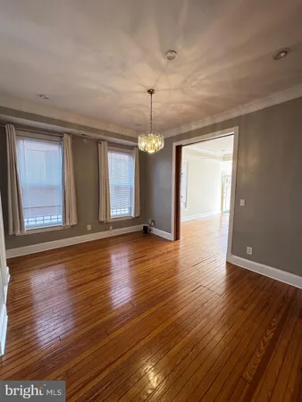 a view of an empty room with wooden floor and fan