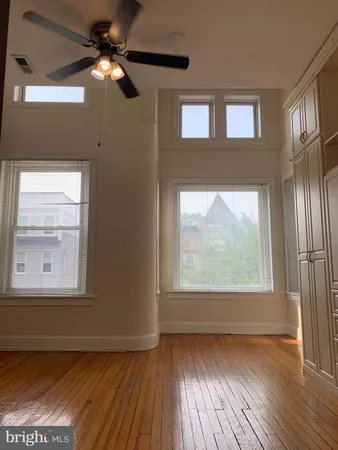 a view of empty room with wooden floor and fan