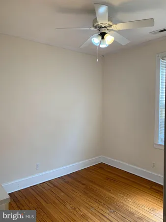 a view of an empty room with wooden floor and cabinet