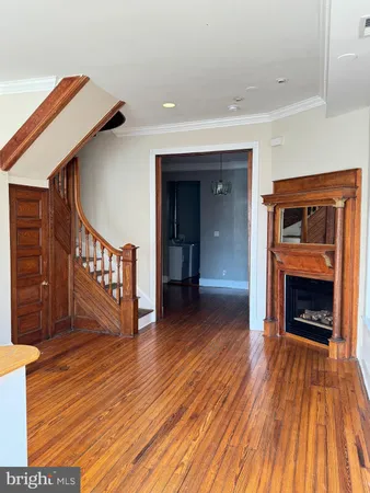 a view of an empty room with wooden floor fireplace and a window