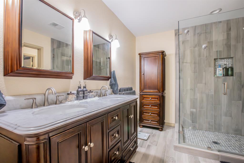 a bathroom with a granite countertop sink a mirror a vanity and a shower