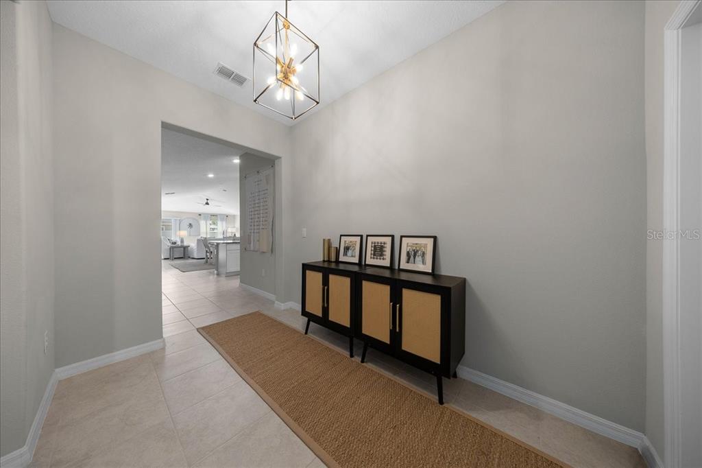 9329 Southwest 57th Terrace Ocala, FL 34476 - Photo 8 of 64 a view of a hallway with wooden floor and a chandelier