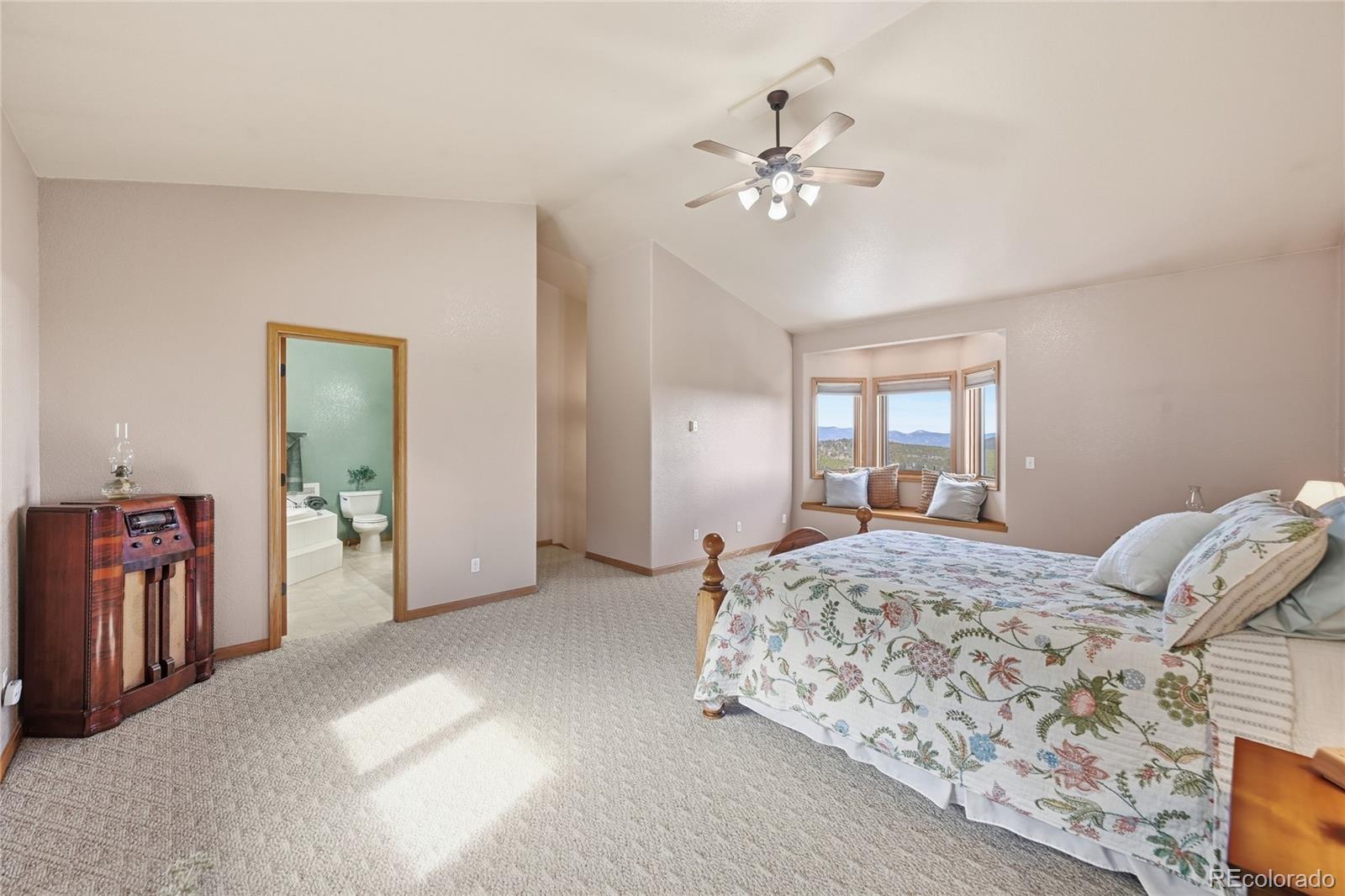31842 Steven Way Conifer, CO 80433 - Photo 11 of 19 a spacious bedroom with a large bed and chandelier