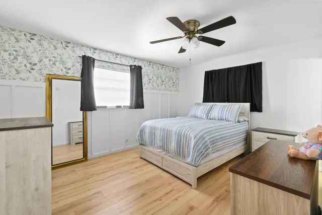 a bedroom with a bed and a ceiling fan with wooden floor