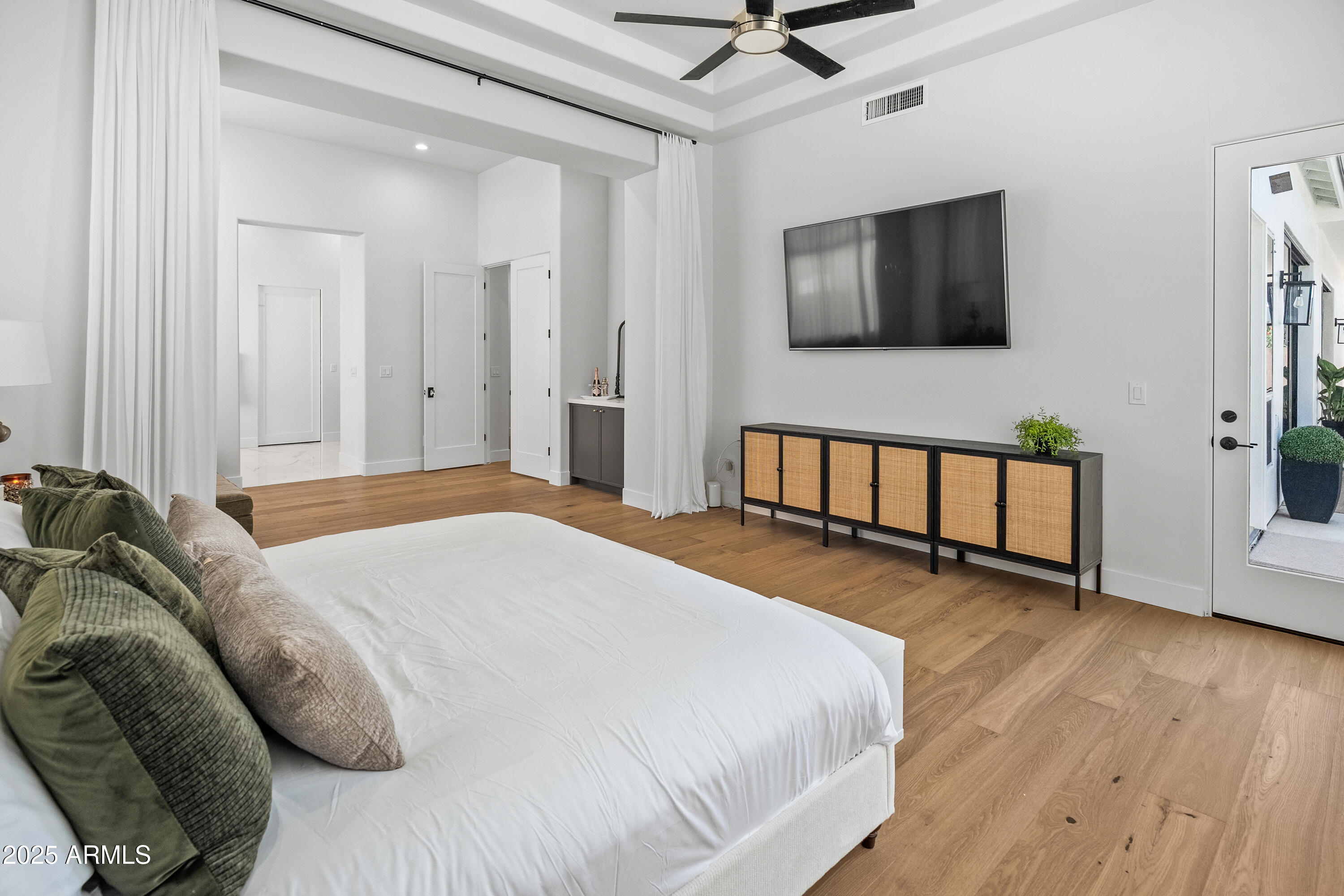 12134 East Mercer Lane Scottsdale, AZ 85259 - Photo 24 of 35 a spacious bedroom with a bed a window and a flat screen tv