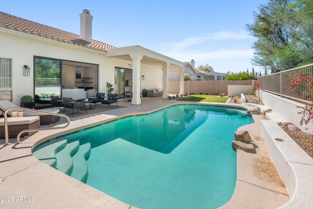 a view of a house with pool lawn chairs and a barbeque