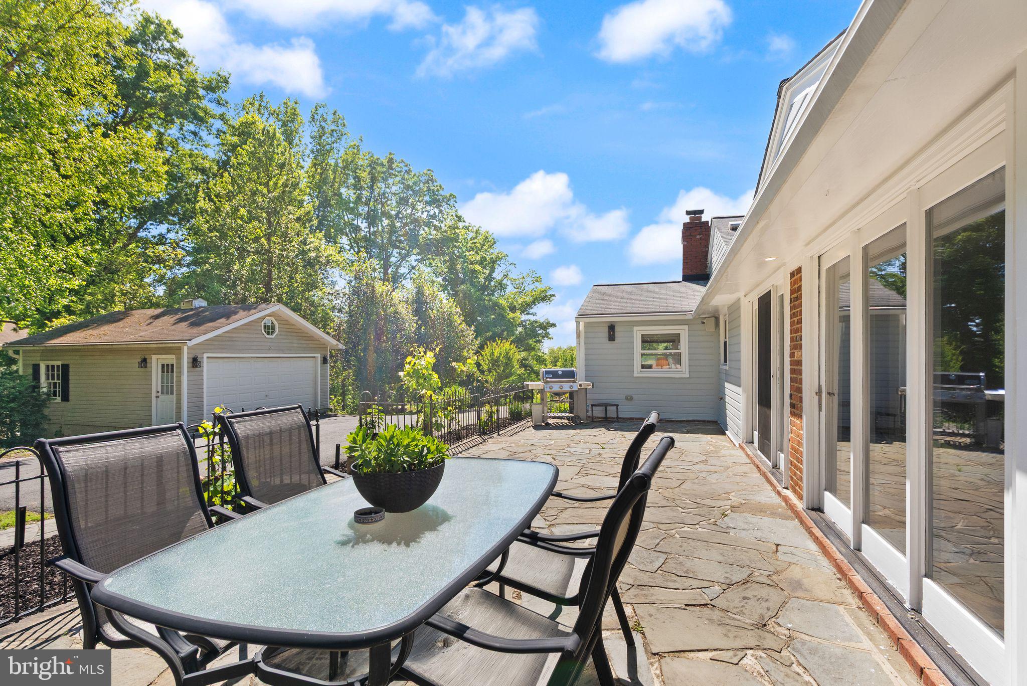815 Seneca Road Great Falls, VA 22066 - Photo 47 of 61 a view of a patio with table and chairs and a barbeque with potted plants