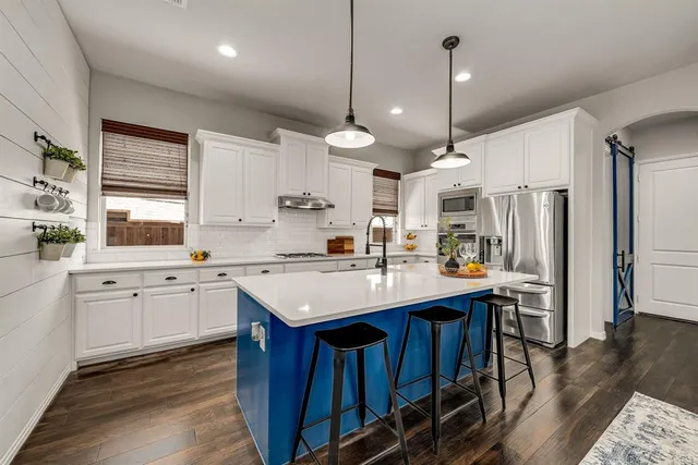 a kitchen with stainless steel appliances kitchen island a large island in the center and wooden floors