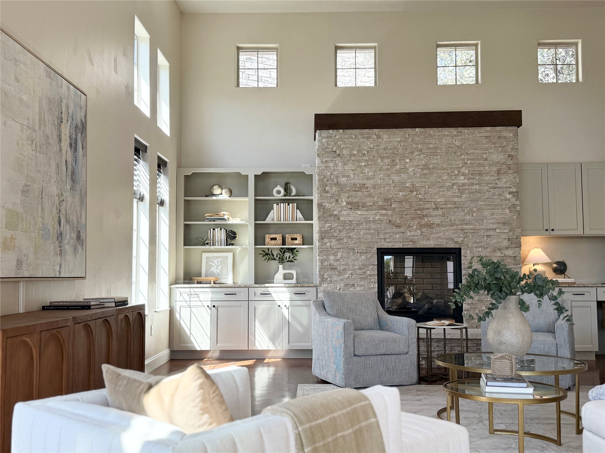 Living room featuring a high ceiling, a fireplace, and light wood finished floors