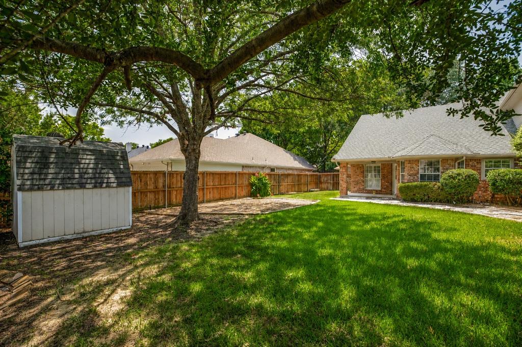 1215 Spring Creek Drive Allen, TX 75002 - Photo 30 of 40 Expansive backyard featuring a mature tree, storage shed, and wood privacy fencing