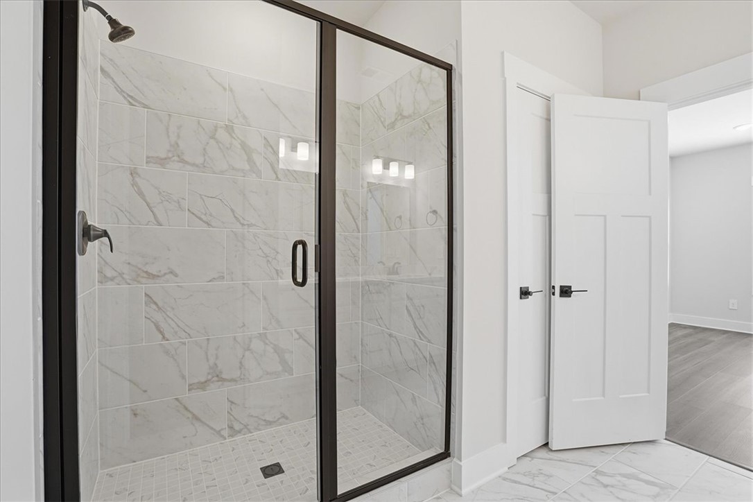 343 Allingham Road Piedmont, SC 29673 - Photo 22 of 37 A frameless glass shower enclosure with marble-style tiling creates a refreshing, contemporary bathing space.