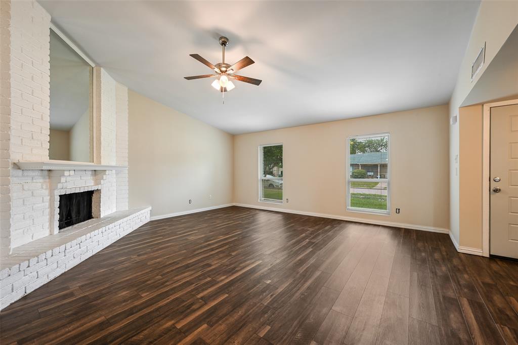 7318 Emory Oak Lane Dallas, TX 75249 - Photo 10 of 28 Spacious living area featuring a whitewashed brick fireplace, vaulted ceiling, and dark wood-finish flooring