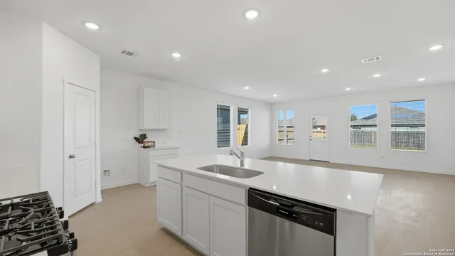 a large white kitchen with a sink stainless steel appliances and a counter space