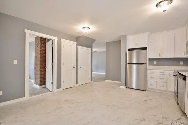 a view of a kitchen with a sink and dishwasher a refrigerator with white cabinets