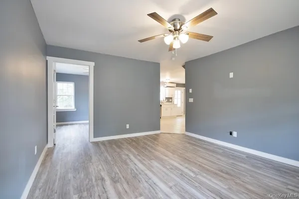 an empty room with wooden floor chandelier fan and windows