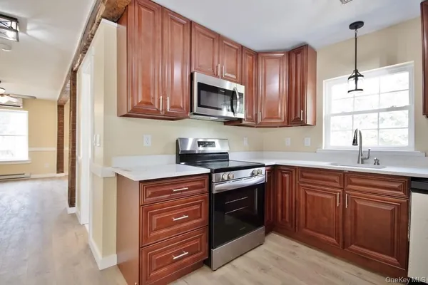 a kitchen with stainless steel appliances granite countertop wooden cabinets a stove a sink and a window