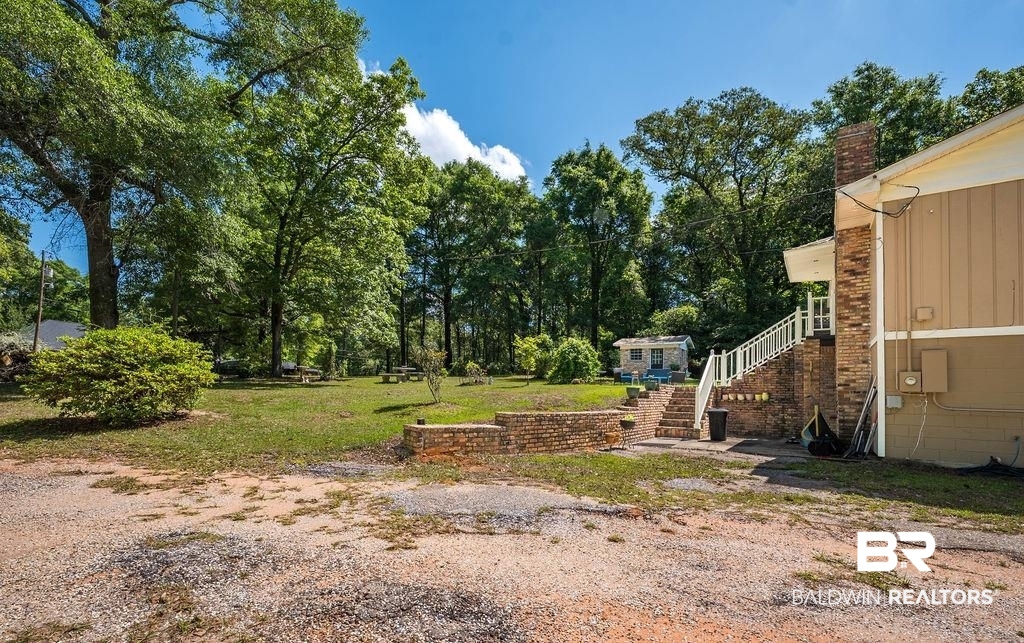 11901 Old Moffat Road Wilmer, AL 36587 - Photo 33 of 39 View of green lawn featuring stairway and view of wooded area