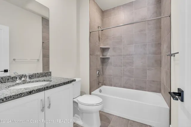 a bathroom with a granite countertop bathtub shower sink vanity and toilet