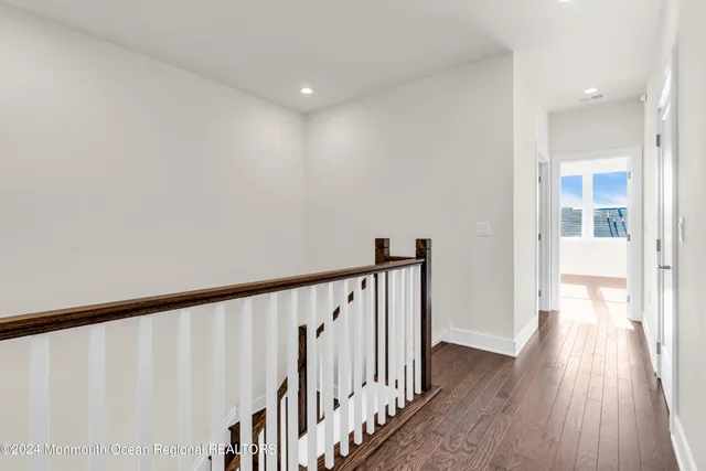 a view of a hallway with wooden floor and staircase