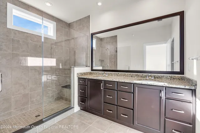 a bathroom with a granite countertop sink a mirror and a glass door shower