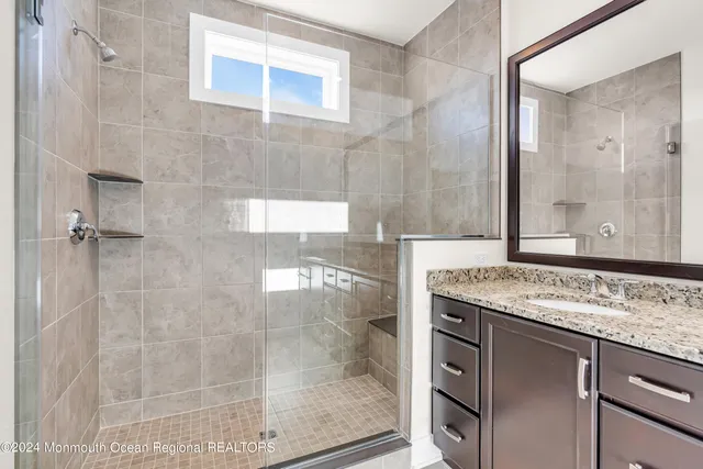 a bathroom with a granite countertop sink a mirror and a shower