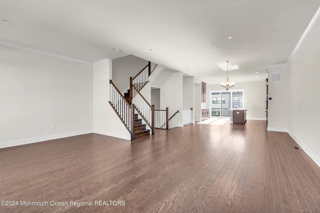 a view of an empty room with wooden floor windows