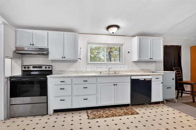 a kitchen with granite countertop white cabinets and appliances