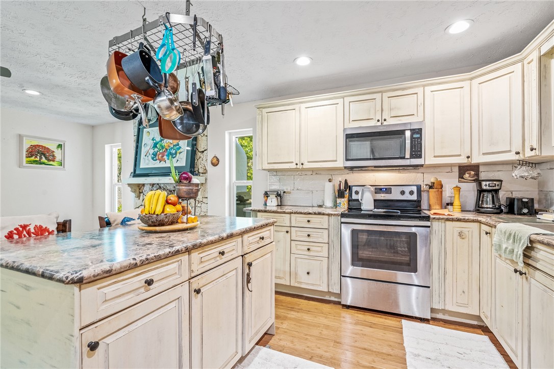 5313 Palm Drive Fort Pierce, FL 34982 - Photo 17 of 36 a kitchen with stainless steel appliances granite countertop a sink a stove top oven a chimney and cabinets