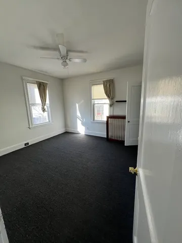 an empty room with windows and ceiling fan