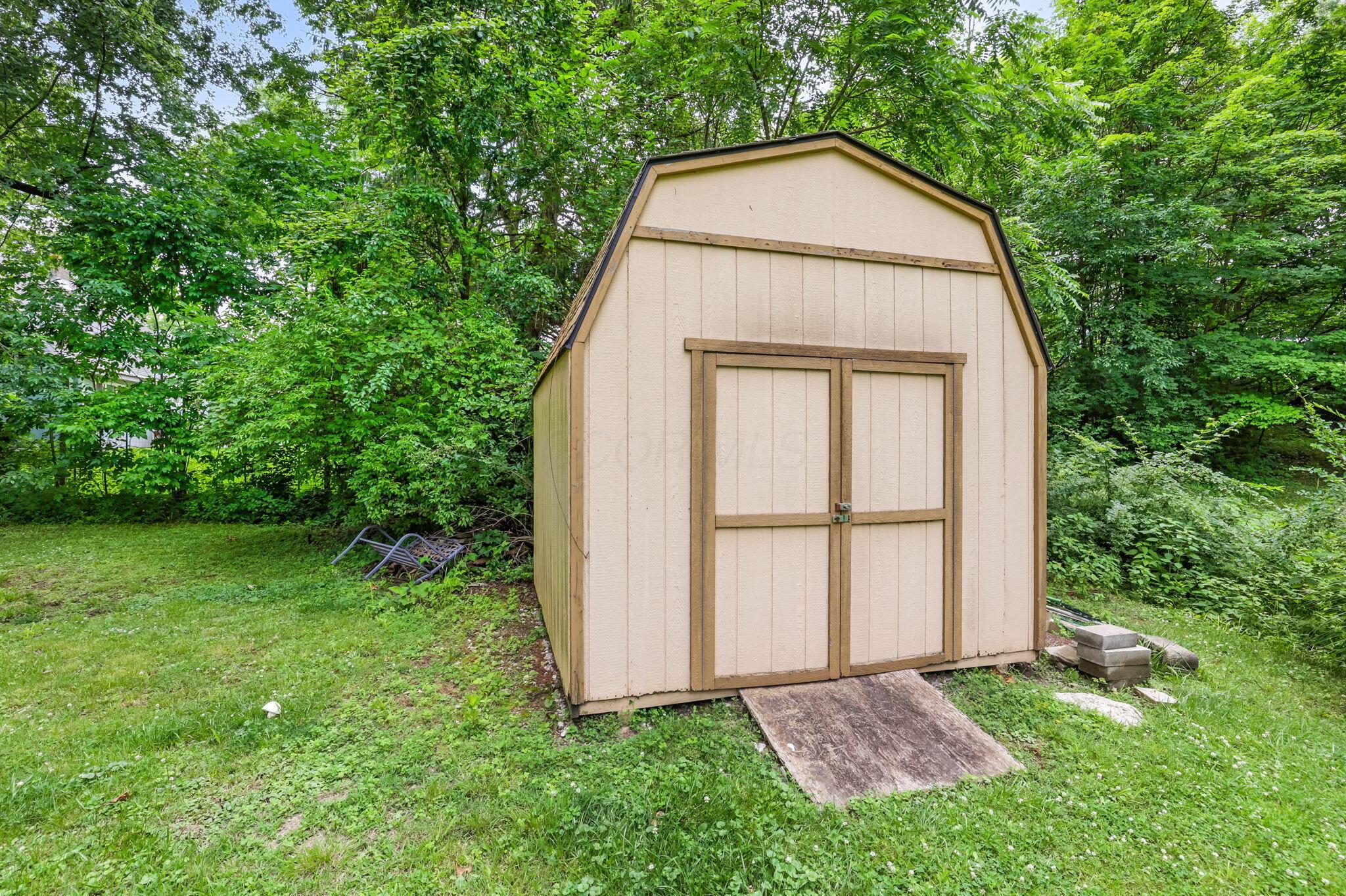 14823 Cleveland Road Southwest Pataskala, OH 43062 - Photo 45 of 57 Gable-style shed with double doors and a wood ramp, set on a grassy lawn surrounded by mature trees