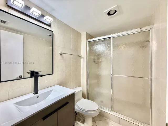 a bathroom with a shower sink vanity mirror and toilet