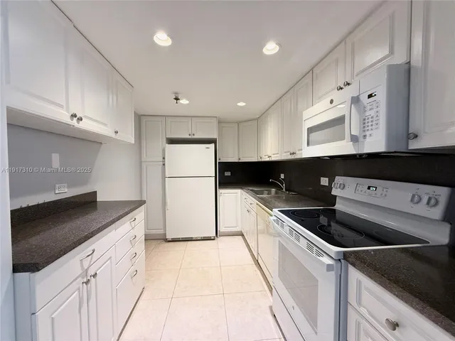 a kitchen with granite countertop a refrigerator and a sink