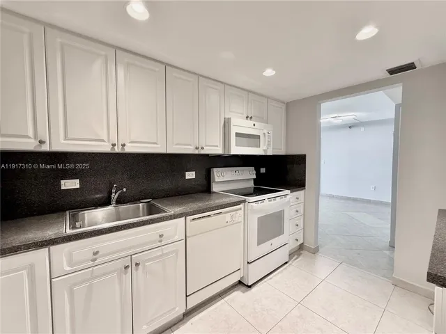 a kitchen with granite countertop white cabinets and sink